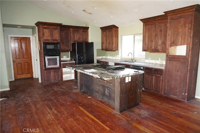 kitchen featuring dark wood-style flooring, a kitchen island, vaulted ceiling, a sink, and black appliances