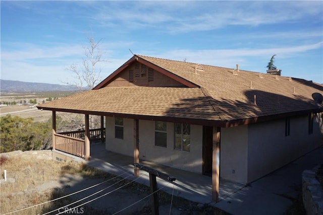 rear view of property featuring a shingled roof