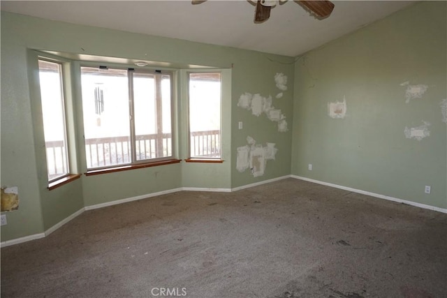 carpeted spare room featuring ceiling fan and baseboards