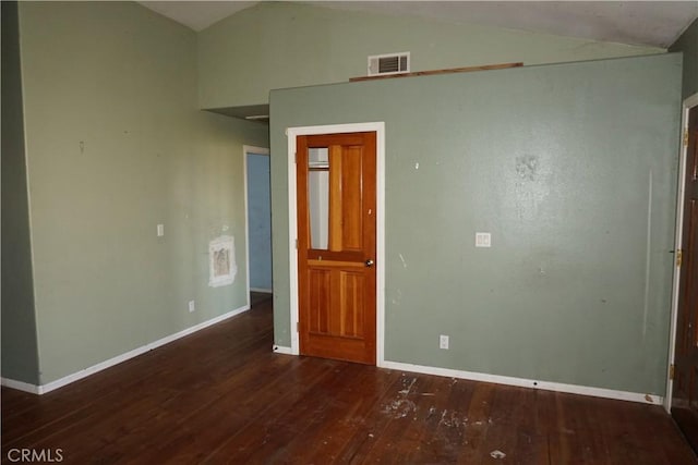 empty room featuring lofted ceiling, baseboards, visible vents, and wood finished floors