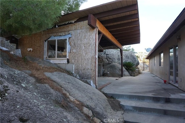 view of side of property featuring stone siding and a patio area