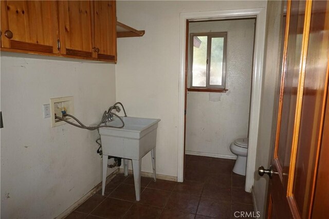 washroom featuring washer hookup and dark tile patterned floors