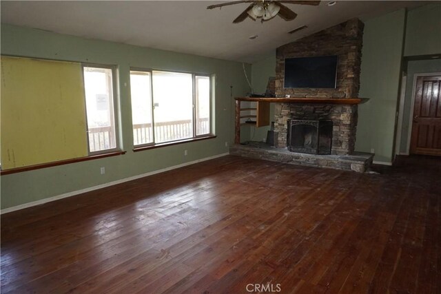 unfurnished living room with ceiling fan, a stone fireplace, lofted ceiling, and dark wood-type flooring