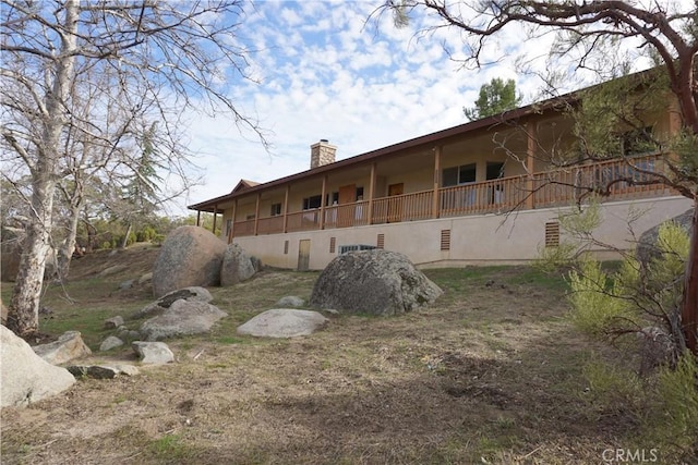 back of property featuring a chimney and stucco siding