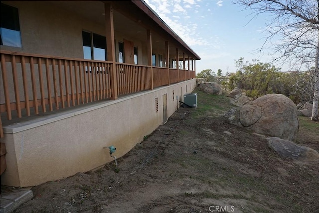 view of side of property with stucco siding and central air condition unit