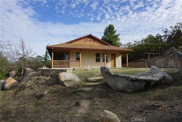 back of property featuring a porch and stucco siding