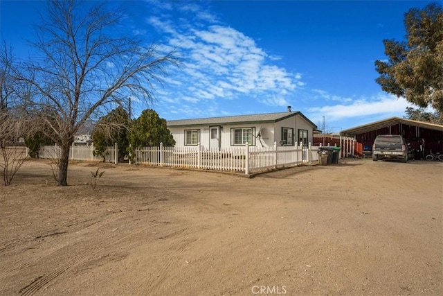 view of front of home with a fenced front yard, a detached carport, and driveway