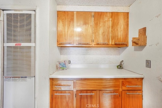 kitchen featuring open shelves, brown cabinetry, a heating unit, and light countertops