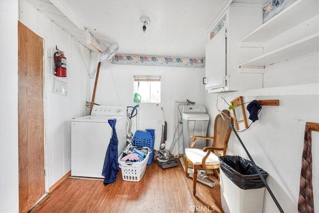 laundry area with cabinet space, washer / dryer, and light wood-style floors