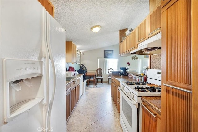 kitchen featuring lofted ceiling, white appliances, brown cabinets, and under cabinet range hood