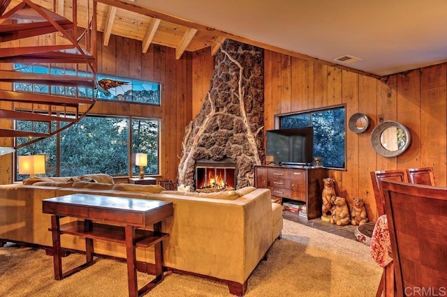 carpeted living room with beam ceiling, wood walls, a fireplace, and wooden ceiling