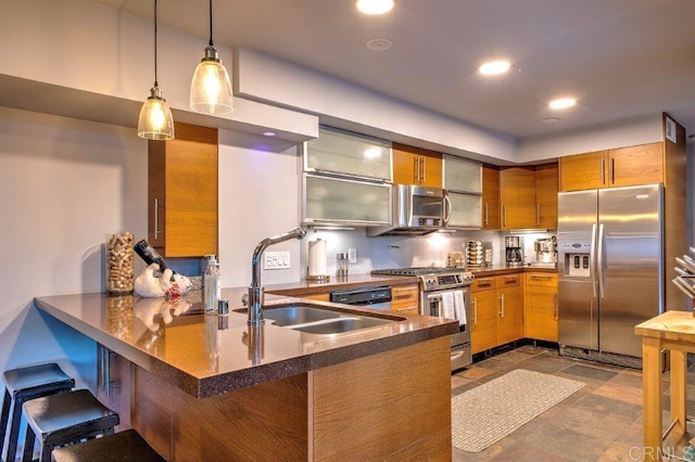 kitchen with sink, stainless steel appliances, kitchen peninsula, pendant lighting, and a kitchen bar