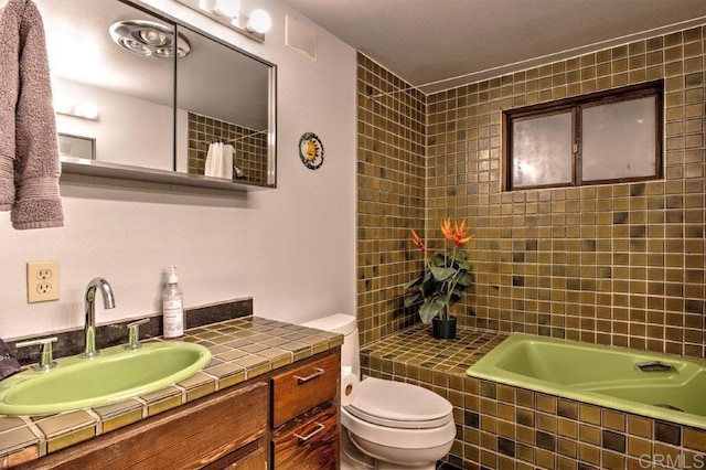 bathroom with vanity, toilet, and tiled tub