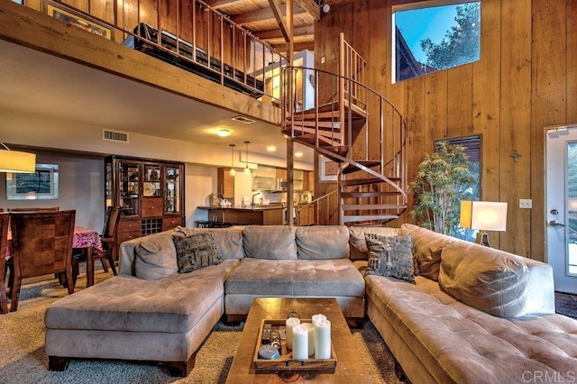 living room with beamed ceiling, wood walls, and a towering ceiling