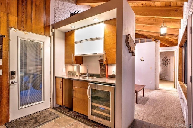 kitchen with beverage cooler, sink, dark colored carpet, wooden ceiling, and beamed ceiling