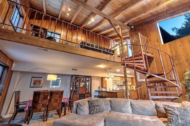 living room featuring beam ceiling, wood ceiling, wooden walls, and a high ceiling