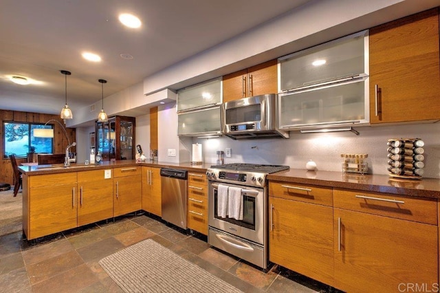 kitchen featuring sink, kitchen peninsula, stainless steel appliances, and hanging light fixtures