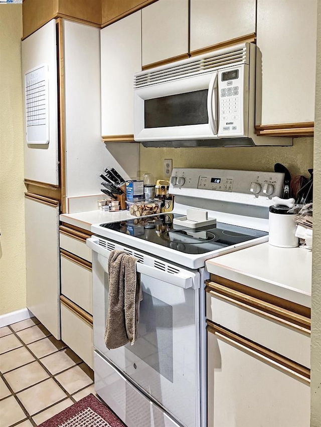 kitchen with white cabinetry, white appliances, and light tile patterned floors