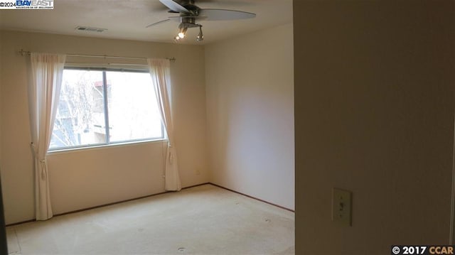 carpeted spare room featuring ceiling fan