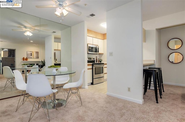 carpeted dining area with ceiling fan