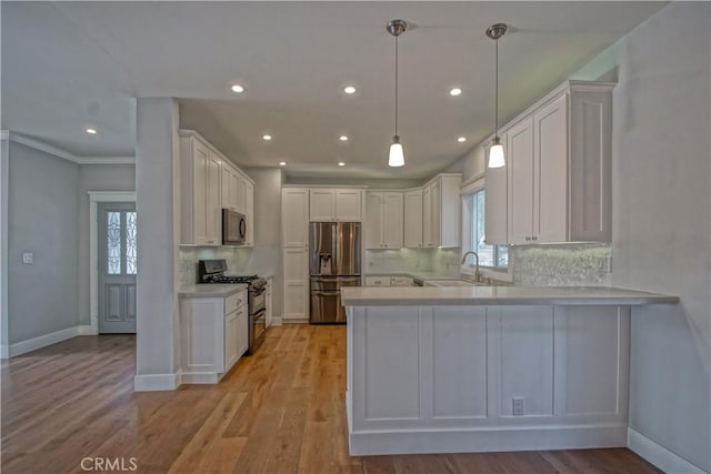 kitchen featuring white cabinetry, sink, stainless steel appliances, light hardwood / wood-style flooring, and kitchen peninsula