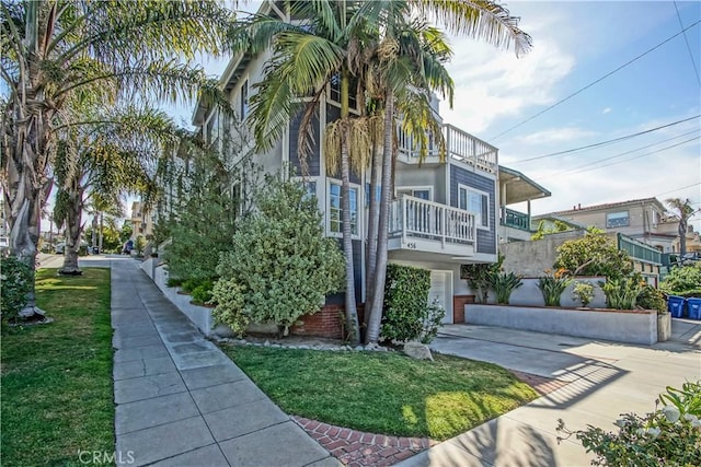 view of side of home featuring a balcony, a garage, and a lawn