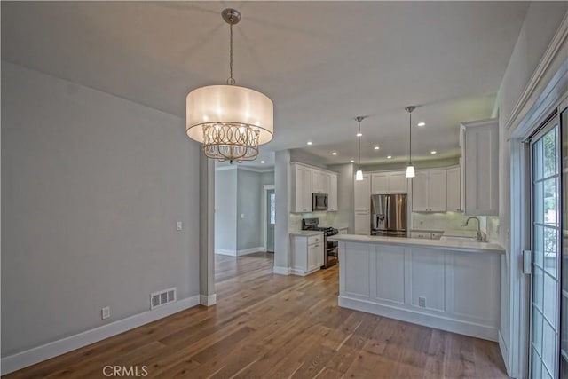 kitchen featuring white cabinetry, light hardwood / wood-style flooring, a chandelier, decorative light fixtures, and appliances with stainless steel finishes