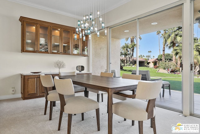 carpeted dining space with ornamental molding and an inviting chandelier