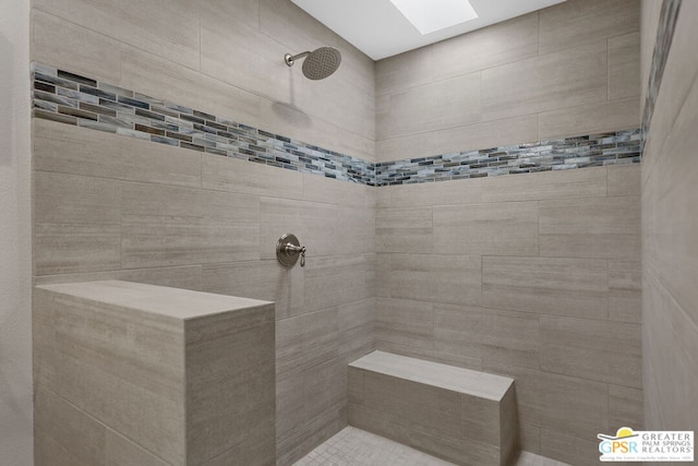 bathroom with a skylight and a tile shower