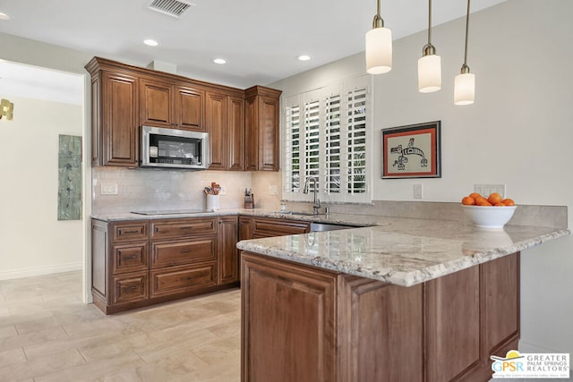 kitchen featuring light stone countertops, decorative light fixtures, black electric stovetop, tasteful backsplash, and kitchen peninsula