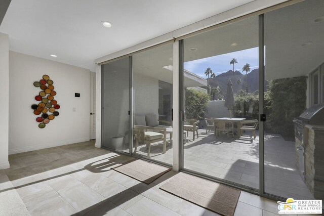 doorway featuring a wall of windows, light tile patterned floors, and a mountain view