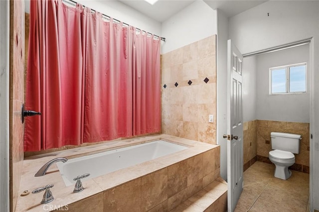 bathroom featuring tile patterned flooring, toilet, tile walls, and tiled bath