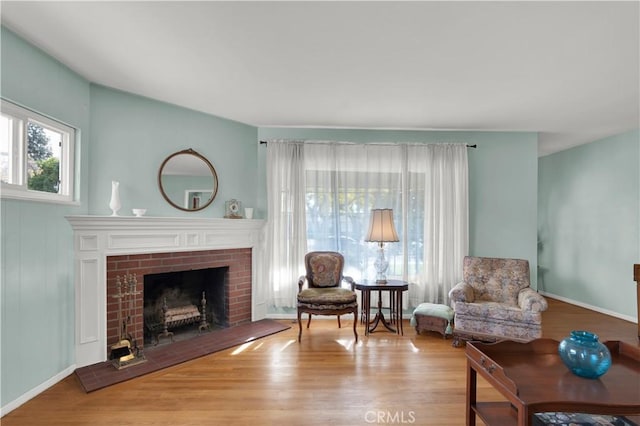 living area with a brick fireplace and light hardwood / wood-style flooring