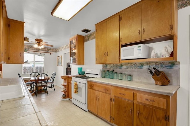 kitchen featuring ceiling fan, sink, white appliances, and tile counters