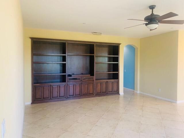 unfurnished living room with light tile patterned floors, ceiling fan, and built in shelves