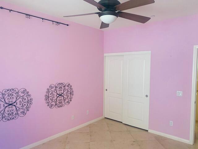 unfurnished bedroom with ceiling fan and a closet