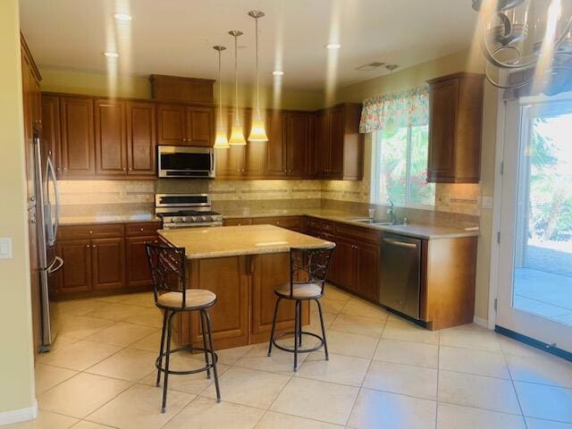 kitchen with a center island, sink, stainless steel appliances, backsplash, and light tile patterned floors