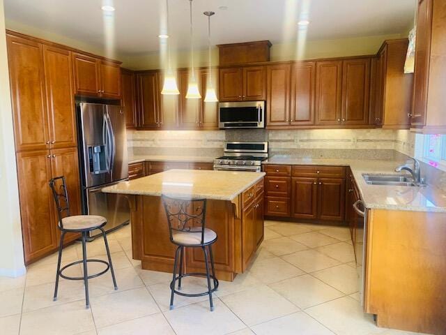 kitchen with sink, a center island, a kitchen breakfast bar, light tile patterned floors, and appliances with stainless steel finishes