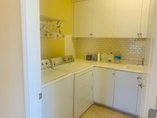 laundry area featuring washer and clothes dryer, cabinets, light tile patterned floors, and sink