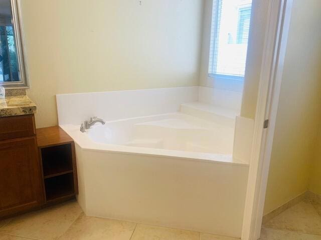 bathroom with tile patterned floors, a washtub, and vanity