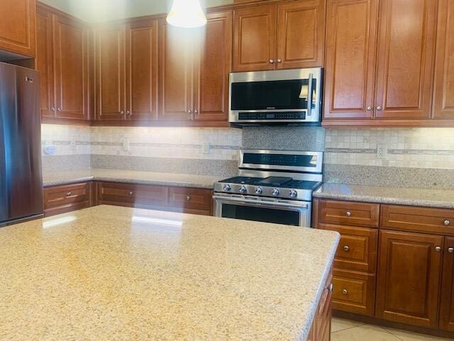 kitchen featuring light stone countertops, backsplash, and stainless steel appliances