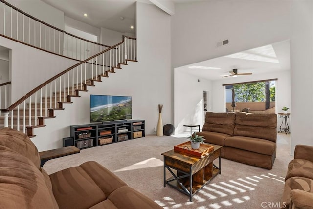 carpeted living room featuring ceiling fan and a high ceiling