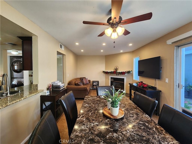 dining area with ceiling fan, stacked washer / drying machine, and sink