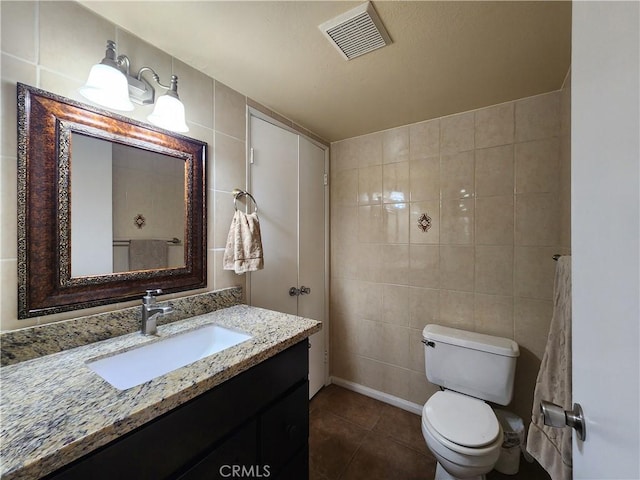 bathroom featuring tile patterned flooring, vanity, tile walls, and toilet