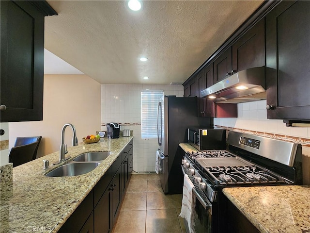 kitchen featuring light stone countertops, sink, stainless steel range with gas cooktop, a textured ceiling, and light tile patterned flooring