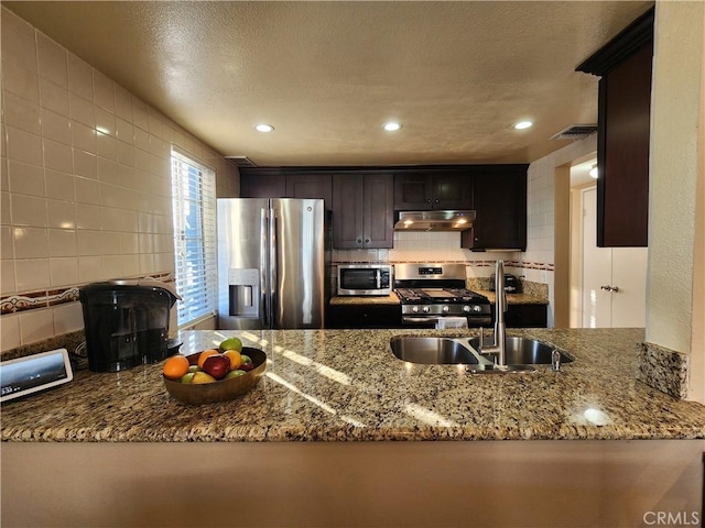 kitchen featuring kitchen peninsula, appliances with stainless steel finishes, light stone counters, and sink