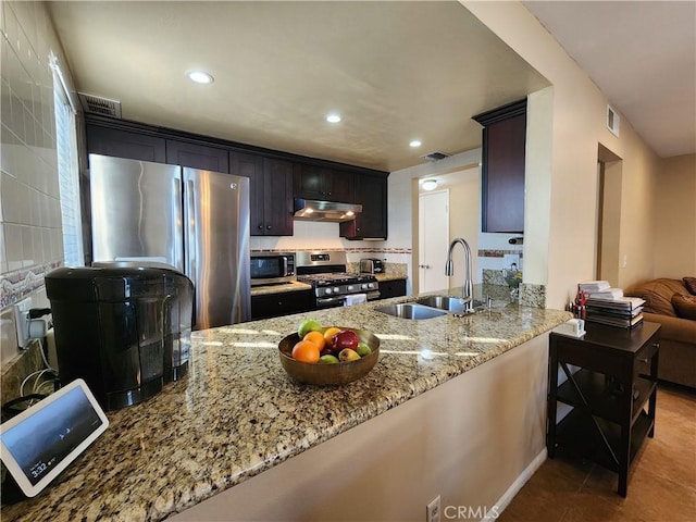 kitchen featuring sink, light stone counters, kitchen peninsula, light tile patterned floors, and appliances with stainless steel finishes