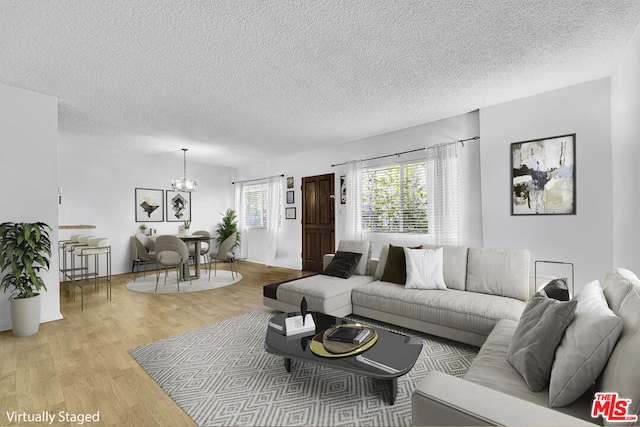 living room featuring light hardwood / wood-style flooring, a textured ceiling, and a notable chandelier