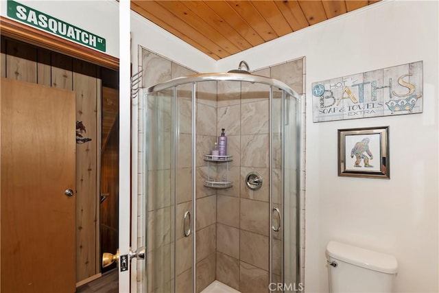 bathroom featuring wooden ceiling, a shower with shower door, and toilet