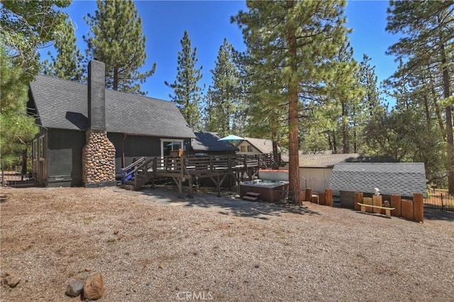 rear view of house featuring a wooden deck and a hot tub